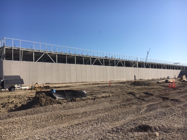 A job site with wall sheathing going up on a structure. There is a blue sky in the image.