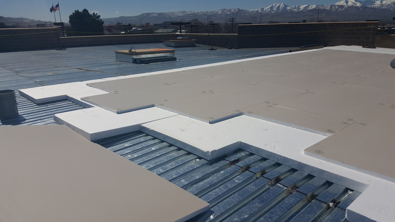 White EPS rigid insulation boards installed on the roof underneath gray cover boards.